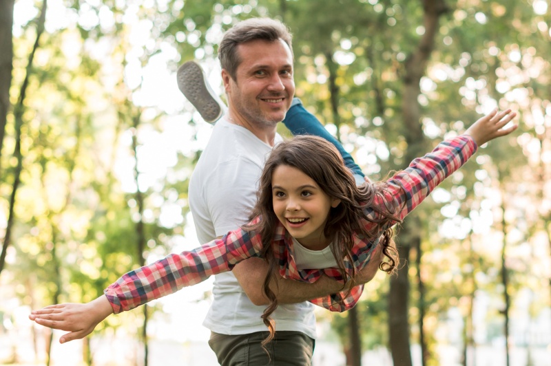smiling-man-carrying-his-cute-daughter-park